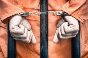 handcuffed prisoner behind bars | Child Sex Assault in Boulder