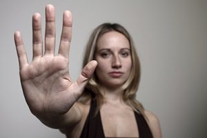 blonde woman holding hand out to say stop | Differences Between Sexual Harassment and Sexual Assault