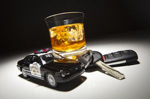Highway Patrol Police Car Next to Alcoholic Drink and Keys Under Spot Light | Colorado Criminal Penalties for DUI Offenses