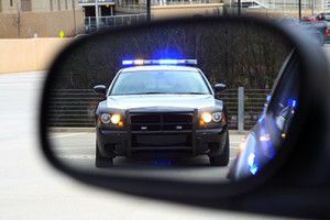 Traffic stop with police car in driver side rear view mirror | Traffic Stop Tips That Will Help You Protect Your Rights